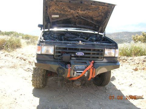 1985 Ford Bronco - This Ford Bronco, likely from the late 1980s, is parked on a dirt road with its hood open.