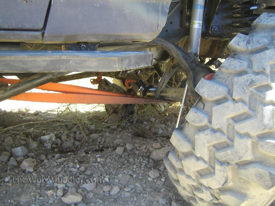 Underbody close-up of a lifted truck with orange strap and mud tire