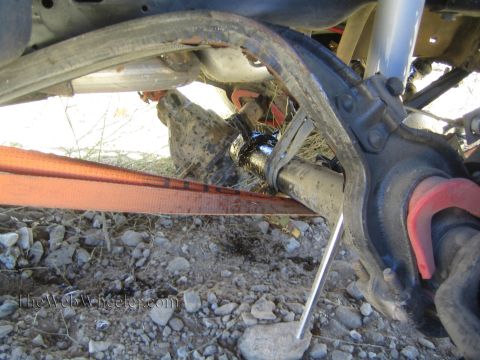 1990 Ford Bronco - Detailed view of an off-road truck's rear axle, driveshaft and suspension with an orange recovery strap below.