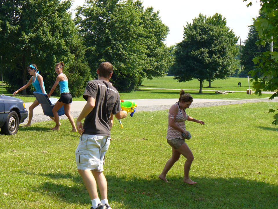 People with water guns in a park, one person carrying a blue object