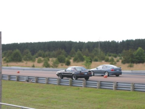 1989 Ford Mustang - A black 1989 Ford Mustang races another car on a track.