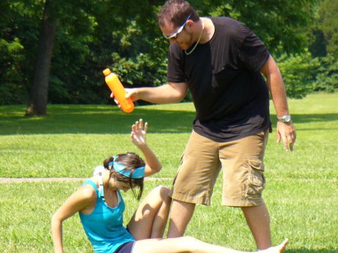 1991 Ford Probe - A man holds an orange bottle over a woman sitting on the grass in a park.