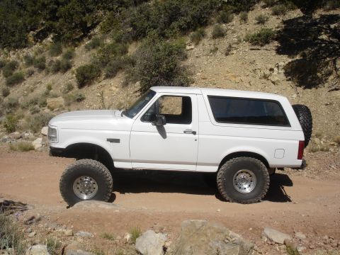 1996 Ford Bronco - White 1996 Ford Bronco driving on a rocky, off-road trail.