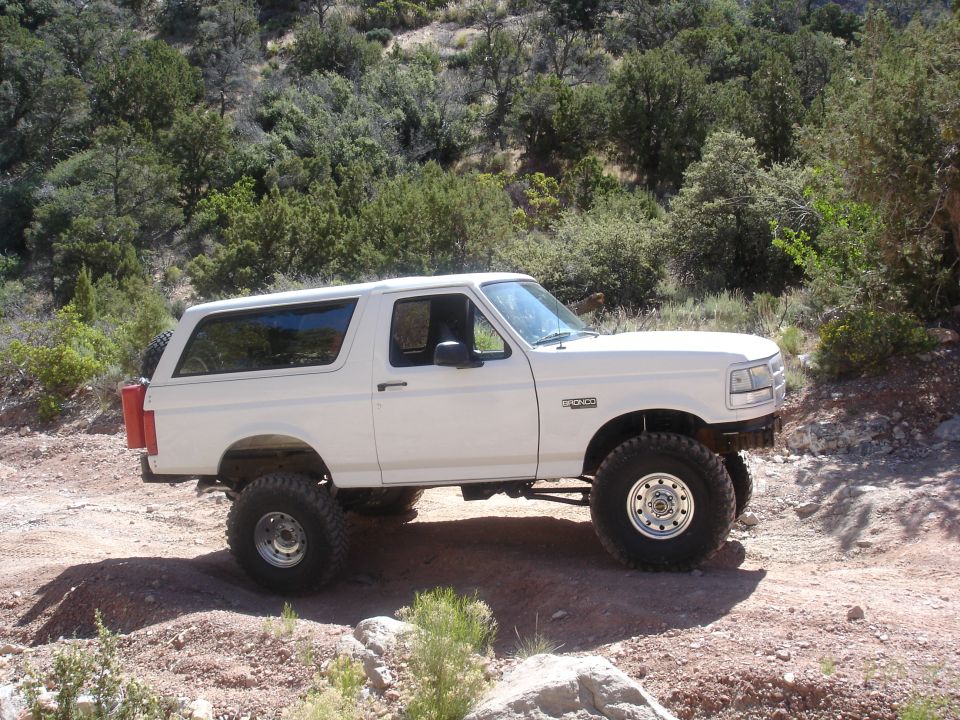 White Ford Bronco with lifted suspension and large tires on a dirt road