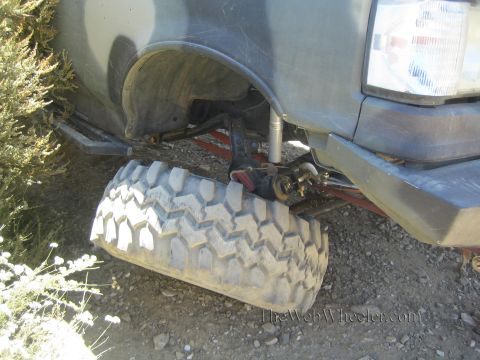 1990 Ford Bronco - truck's front tire is splayed under the fender with a broken steering or suspension link on rocky terrain.