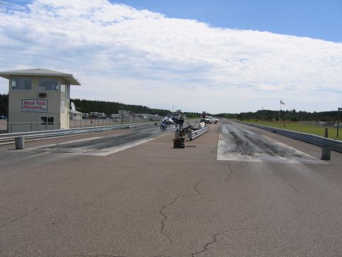 1989 Ford Mustang - A drag strip scene at Rock Falls Raceway under a partly cloudy sky.