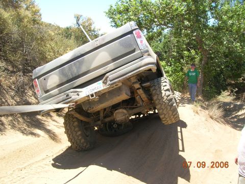 1985 Ford Bronco - A man watches as a lifted truck gets stuck on a sandy incline during an off-road excursion.