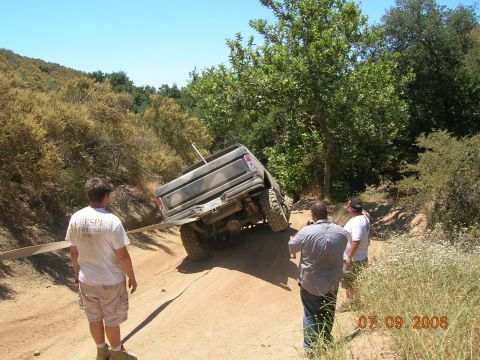 1985 Ford Bronco - A truck is stuck on a steep dirt path, with onlookers observing the situation.