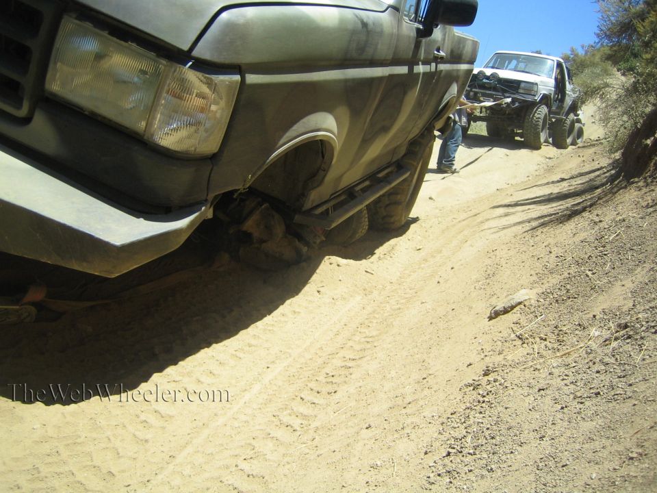 Close-up of camo Ford pickup front fender and tire on a dirt trail