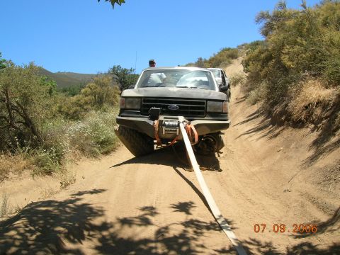 1985 Ford Bronco - A Ford F-Series truck is being pulled out of a ditch on a sunny day.