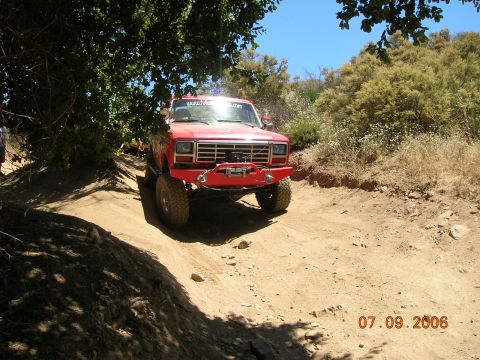 1985 Ford Bronco - Red pickup truck with winch bumper on a dirt trail. Date stamp reads 07.09.2006.