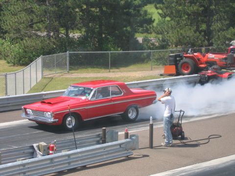 1989 Ford Mustang - A red 1965 Plymouth Belvedere II coupe performs a burnout on the drag strip, with a tractor and ATV visible in the background.