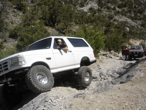 1996 Ford Bronco - A white Ford Bronco navigates a rocky trail, with another vehicle visible in the background.