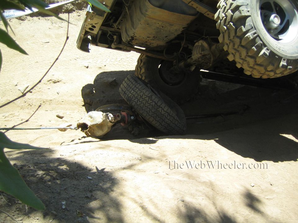 Underbody of an off-road truck with a detached wheel and axle on the ground