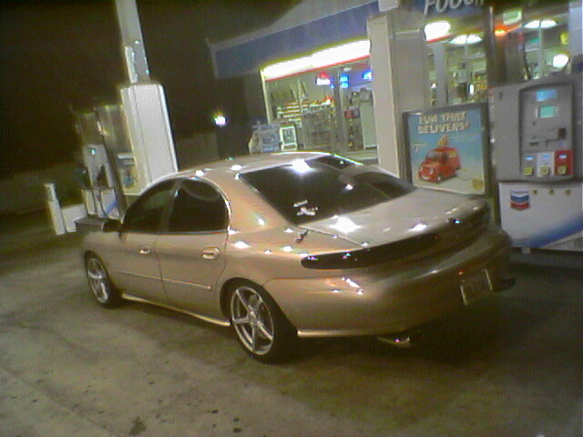 Tan 1998 Mercury Sable sedan, rear 3/4 view, at a gas station