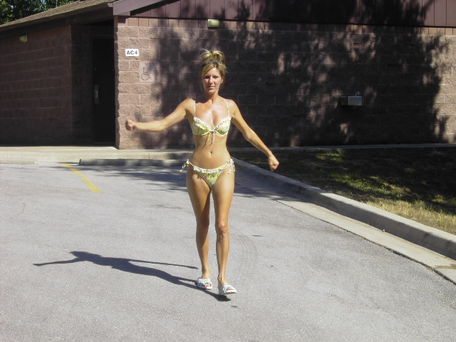 Person walking across a parking lot in front of a brick building