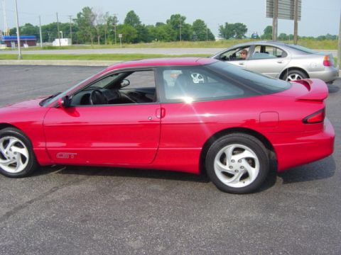 1995 Ford Probe - A red 1995 Ford Probe GT is parked in a lot, with another car visible in the background.
