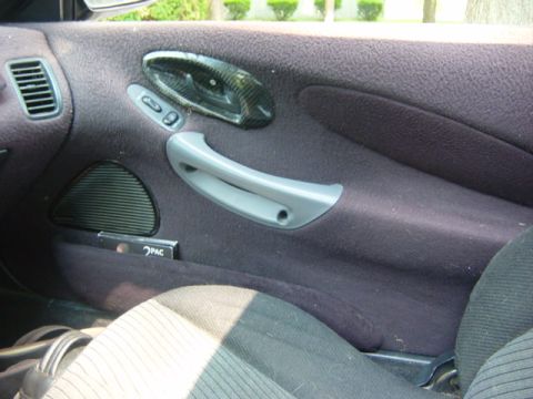 1995 Ford Probe - Close-up of a car's interior door panel, showing the handle and speaker grille.