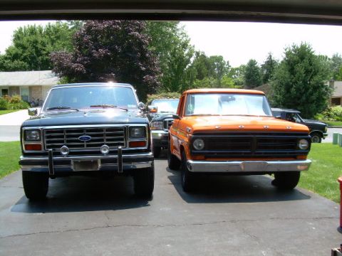 1984 Ford Bronco - Two classic Ford trucks, a Bronco and a pickup, are parked side-by-side in a driveway.