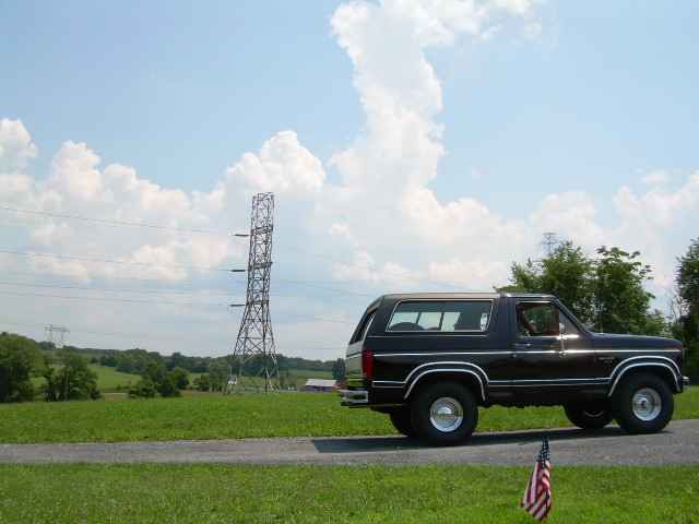Black SUV parked on a road with a power tower in the background