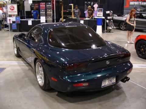 1995 Ford Taurus - Dark green Mazda RX-7 at a car show, with a red sports car visible nearby.