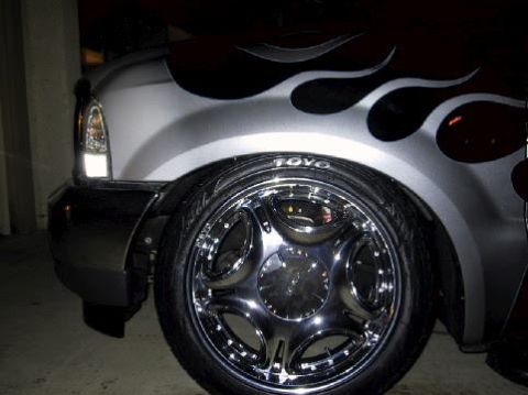 2001 Ford Excursion - A silver 2001 Ford Excursion is shown from the front passenger side, flame decals and custom chrome wheels.