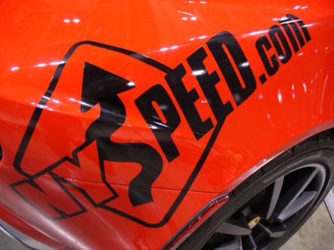 1995 Ford Taurus - Orange car side panel displays a black 'SPEED.com' graphic with an arrow. The vehicle's wheel and tire are also visible.