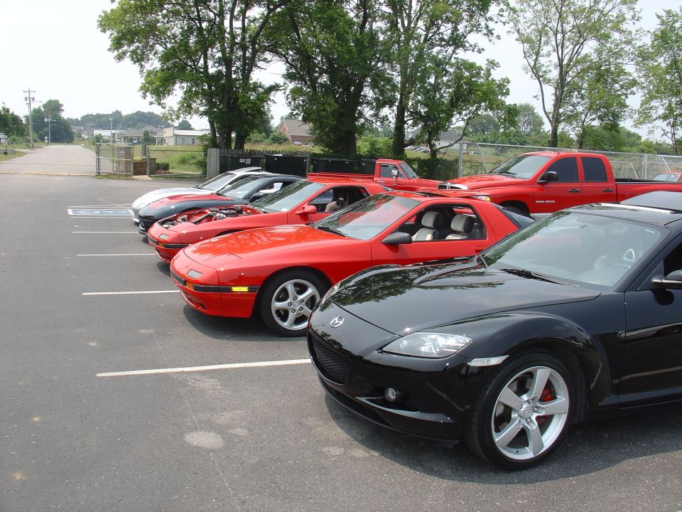 Row of parked sports cars including red FC RX-7, black RX-8 and red pickup