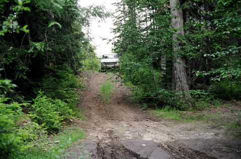 1979 Ford Bronco - A 1979 Ford Bronco navigates a challenging muddy path through a dense forest.
