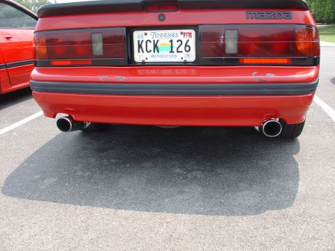 1986 Mazda RX-7 - The rear of a red 1986 Mazda RX-7 is shown, dual exhaust pipes and a Tennessee license plate.