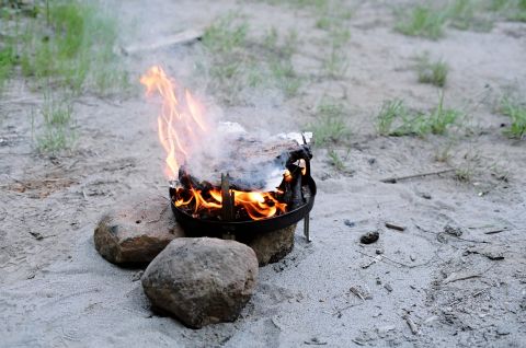 1979 Ford Bronco - Campfire cooking in a Dutch oven on sandy terrain, with a Supermotors.net watermark.