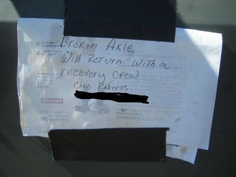 1990 Ford Bronco - Photo of a handwritten note taped to a vehicle saying the truck has a broken axle and the owner will return with a recovery crew.