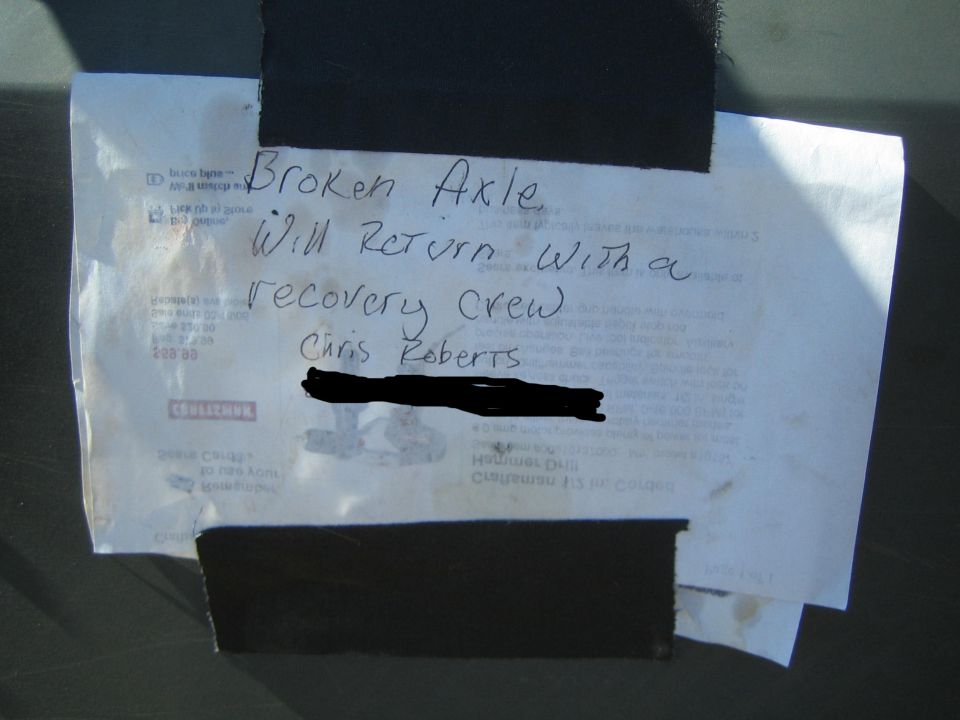 Handwritten note taped to a vehicle reading 'Broken Axle, will return with a recovery crew, Chris Roberts'