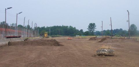 1978 Ford Bronco - Construction site with dirt mounds and a yellow excavator under a cloudy sky.