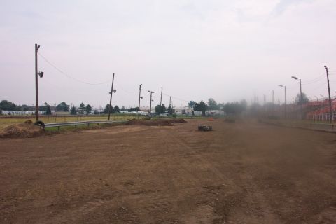 1978 Ford Bronco - A view of a dirt track, complete with utility poles and distant stadium seating, under an overcast sky.