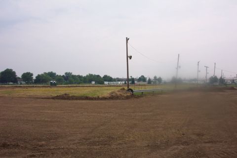 1978 Ford Bronco - Outdoor scene of a dirt track with a portable toilet and utility poles under a hazy sky.