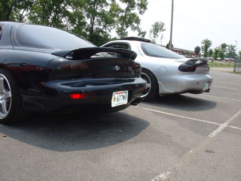 1986 Mazda RX-7 - Two Mazda RX-7s, likely FD generation, are parked together, their rear profiles and distinctive spoilers.