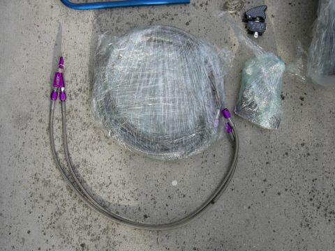 1996 Ford Probe - Automotive parts, including a wrapped disc and braided lines, are laid out on a concrete surface.