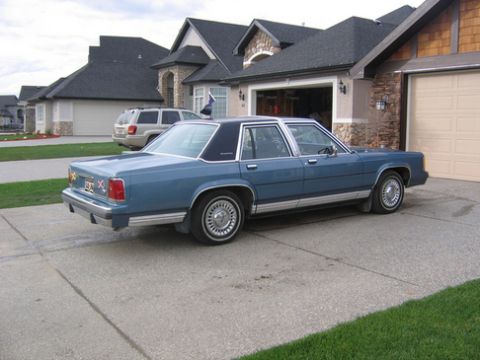 1988 Ford Crown Victoria LTD - A blue 1988 Ford Crown Victoria LTD is parked in a suburban driveway next to a house and another vehicle.
