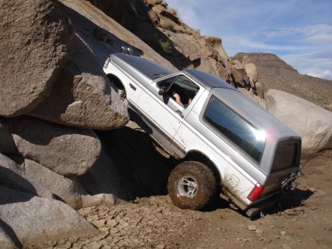 1984 Ford Bronco - This SUV navigates a challenging rocky terrain, appearing to be a 1987 model.