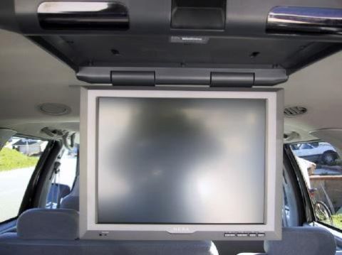 2001 Ford Excursion - The interior of a vehicle features a flip-down video screen mounted to the ceiling.