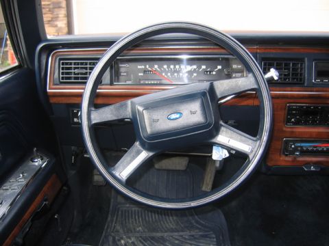 1988 Ford Crown Victoria LTD - The interior of a 1988 Ford Crown Victoria LTD shows its dashboard, steering wheel, and wood trim details.