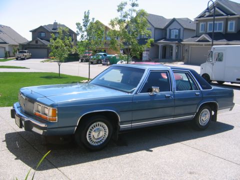 1988 Ford Crown Victoria LTD - A blue 1988 Ford Crown Victoria LTD sedan is parked in a suburban driveway.