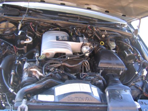 1988 Ford Crown Victoria LTD - The engine bay of a vehicle, a 5.0 liter intake manifold and a "CAUTION FAN" warning label.