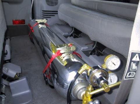 2001 Ford Excursion - Interior view of a vehicle showing a large chrome tank with gauges and red straps.