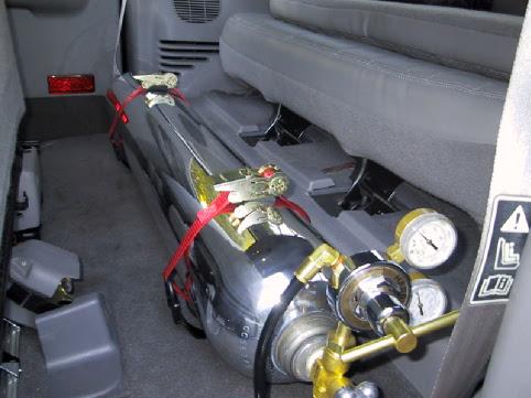 Chrome gas tank with gauges strapped to gray SUV rear floor