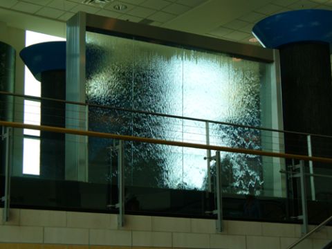 1995 Ford Taurus - A large indoor waterfall is illuminated, with water cascading down a textured glass surface.