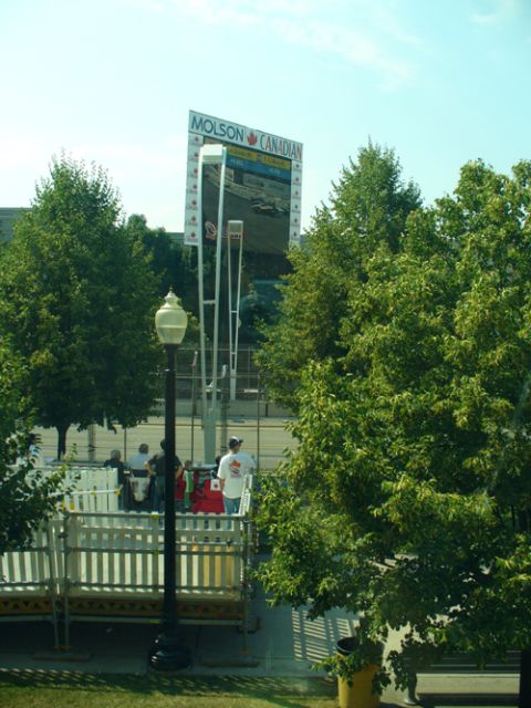 1995 Ford Taurus - A large Molson Canadian scoreboard displays a race scene, surrounded by trees and a lamppost.