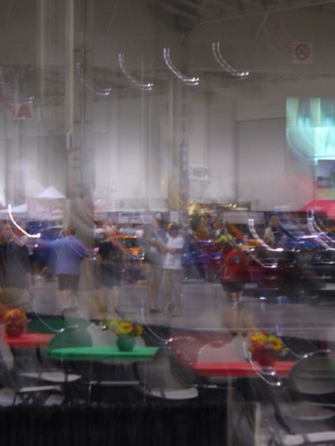 1995 Ford Taurus - An indoor exhibition hall displays multiple vehicles and attendees, with tables set up in the foreground.