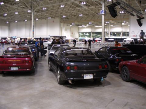 1995 Ford Taurus - Several cars are parked indoors at what appears to be a car show or exhibition.